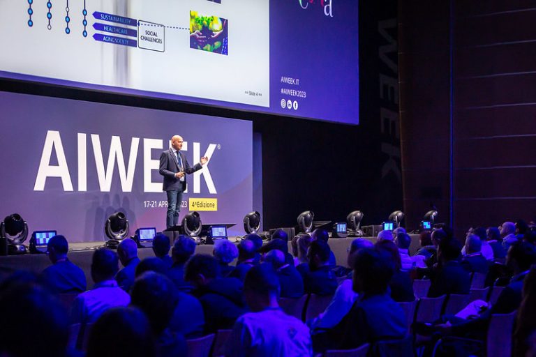 Speaker alla conferenza AI Week 2024 di Rimini parla di fronte a un pubblico numeroso su temi di Intelligenza Artificiale